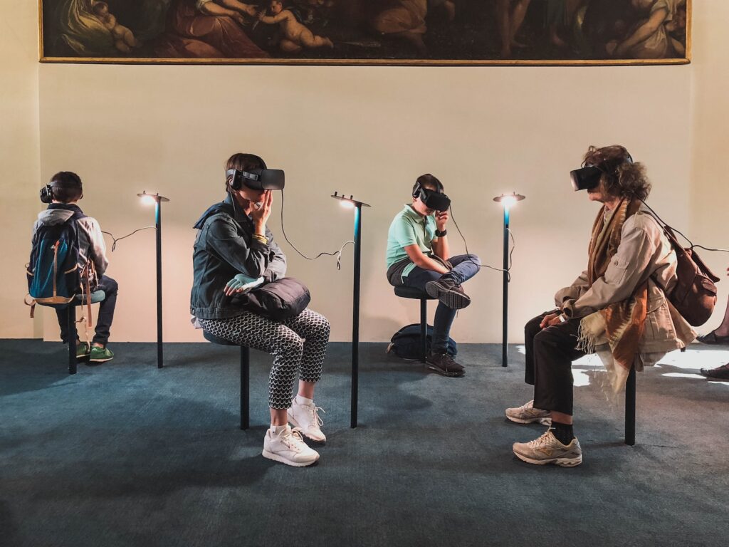 Humans adapt to emerging technologies and often create novel ways to use these innovations. Image of a group using VR headsets to experience an art exhibit together. 