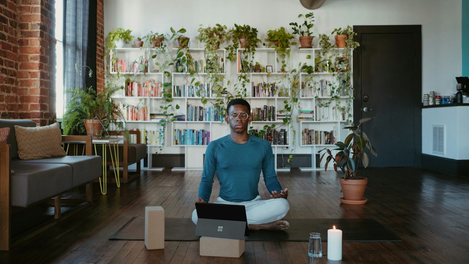 Image Description: self-care, a man sitting on a yoga mat with a laptop in front of him